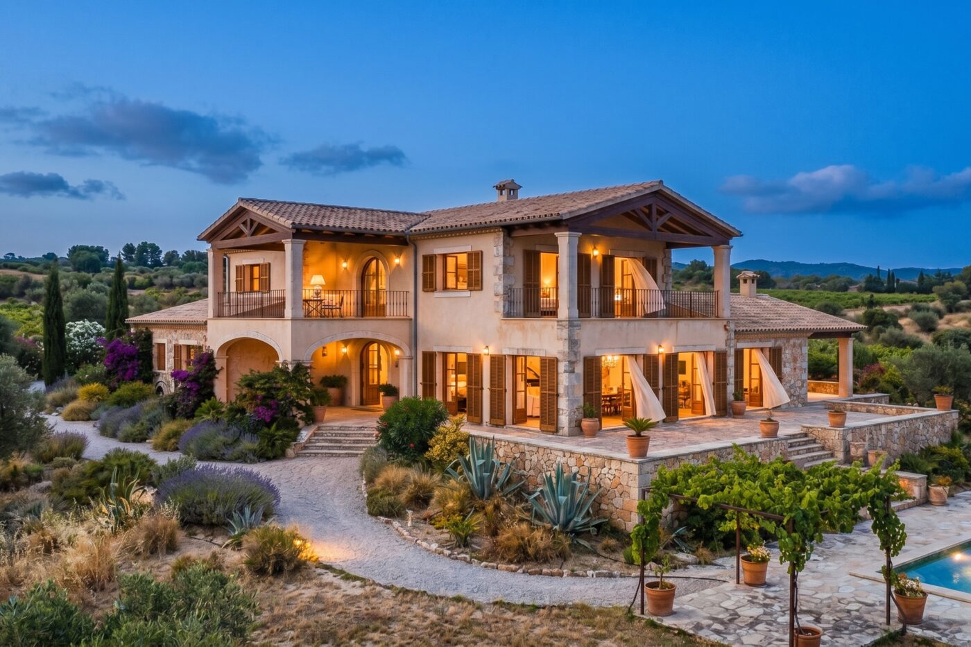 The same villa at dusk with warm interior lights glowing as the air cools outside.